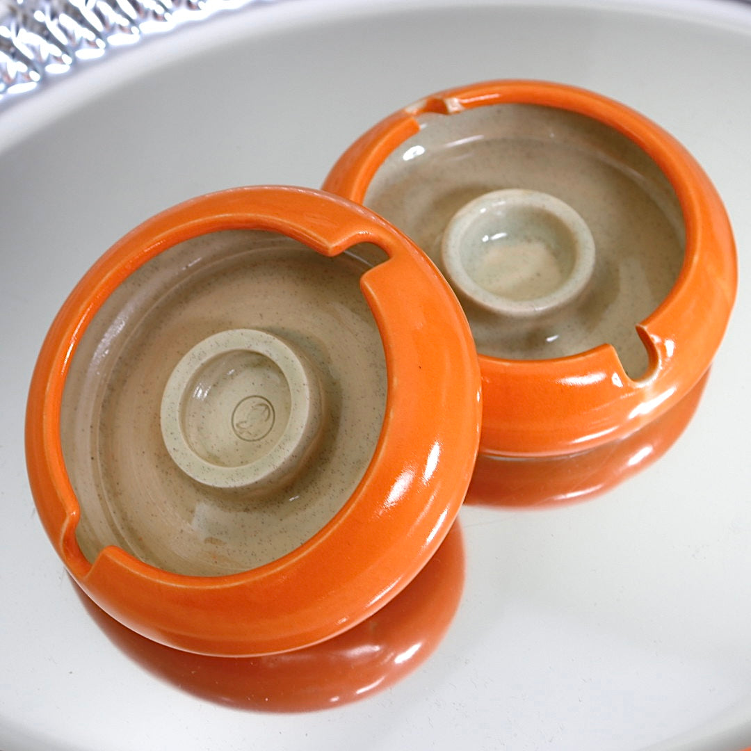 Vibrant orange designer ashtray with a sculptural form, ideal for stacking on coffee tables, accenting interiors, or holding jewelry.